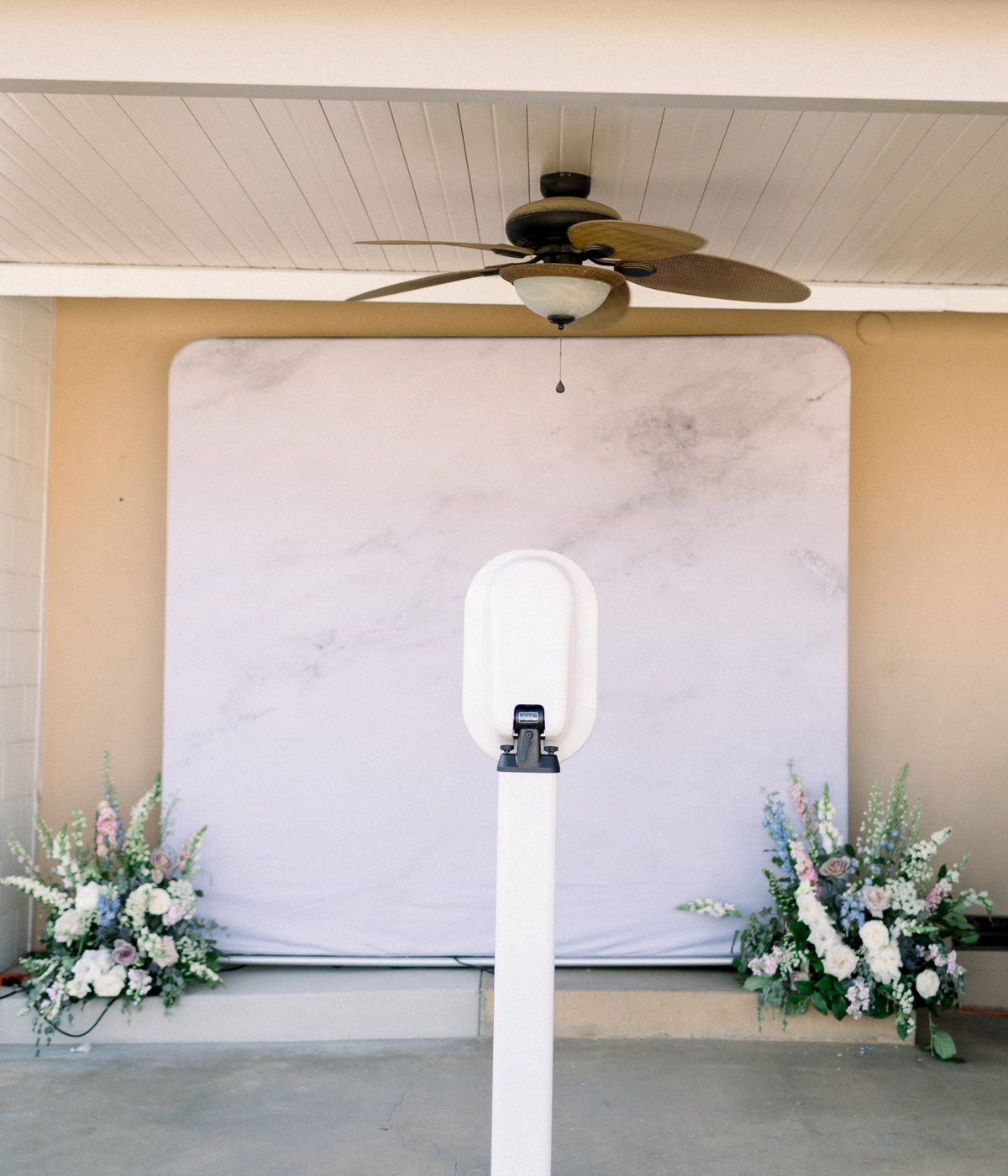 The booth set up under a covered patio against a white backdrop, with flower arrangements on either side